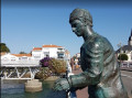 Statue de l'homme en bronze, accoudé à la rambarde